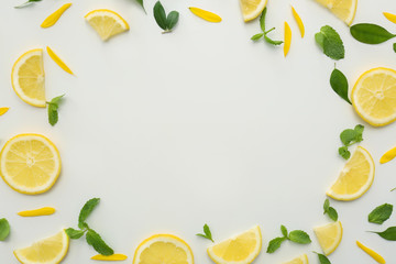 Frame made of lemon slices and green leaves on white background