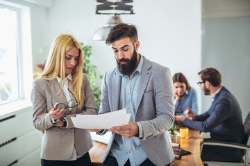 Portrait of two young businesspeople while colleague in background