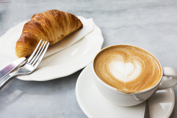 Hot coffee and croissants on a marble table.