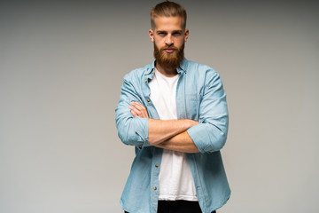 Portrait of happy fashionable handsome man in jeans shirt crossing hands and look at camera.