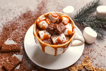 Cup of hot chocolate with marshmallows and caramel on table