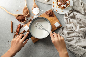 Woman preparing hot chocolate on grey table