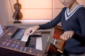 young artist musician woman setting up acoustic guitar strings with keyboard sound in music room.