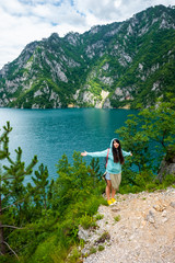 Fototapeta na wymiar beautiful woman standing with open arms near Piva Lake (Pivsko Jezero) in Montenegro