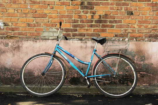 old rusty bike leaned against a brick wall