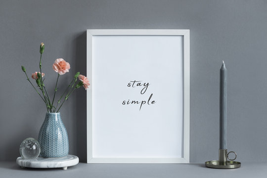 Stylish and minimalistic composition of mock up photo frame with flowers in vase and candle. Modern concept of mockup frame. 
