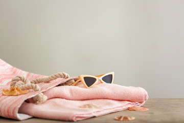 Clean soft towels and beach accessories on light background