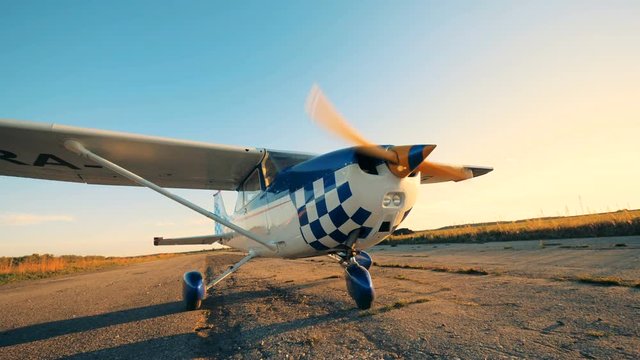 Airplane with rotating propeller. Working plane standing on a runway before flight.