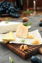 Wooden board with different types of cheese on table