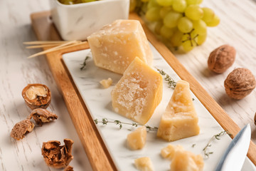 Board with tasty cheese on white wooden table