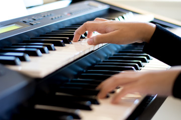 Young artist musician woman hands playing the piano in music room.