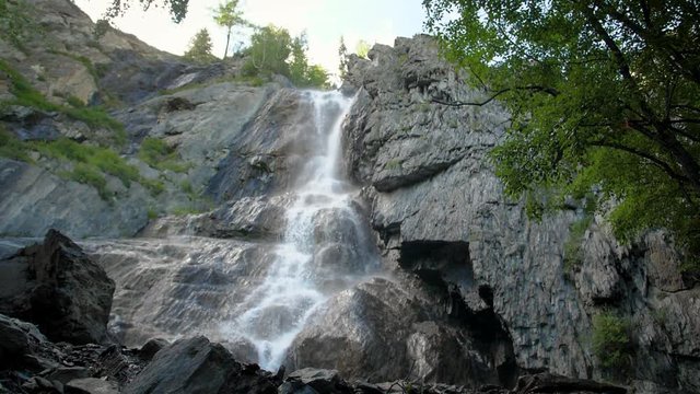 waterfall white water black rocks slow tilt down. Cascade waterfall slow motion. Streams of water among the mountains, huge boulders. 180fps
