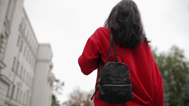 Woman wear little backpack walking in city street, rear view