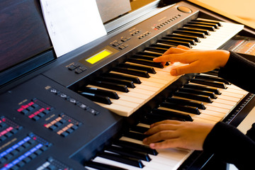 Young artist musician woman hands playing the electone in music room.