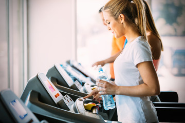 Young woman drinking water while exercising