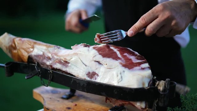 Food service worker cutting ham for party. The waiter preparation food in buffet for customer in hotel or restaurant. 4K UHD