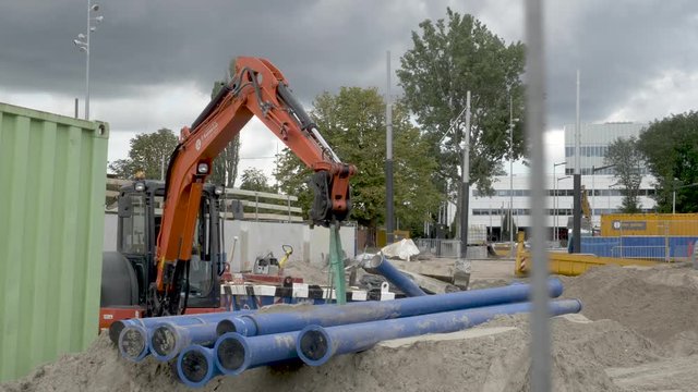 An excavator at a construction site in Amsterdam. The Amstel station is being renovated, new tramlines are build. A slow pan to the right.