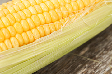 Fresh corn on cobs on rustic wooden table, closeup