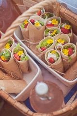 A beautiful picnic basket with tasty, healthy and fresh vegetarian wrap food with eatable flowers...