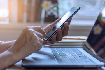 Casual businesswoman hand using mobile smartphone, work on laptop computer, browsing internet application in modern office. 