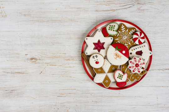 Plate with various colorful christmas gingerbread isolated on wooden background