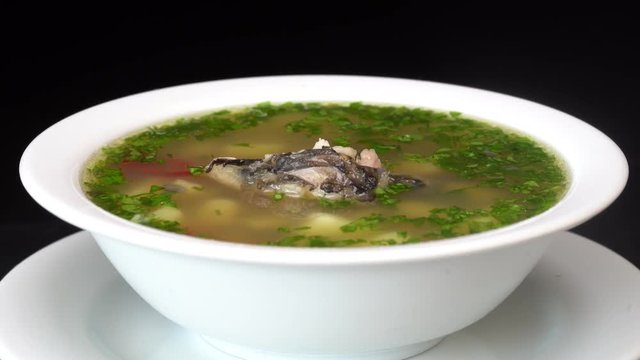 Fish soup with vegetables. Healthy food, fish soup with carrot, pepper, herbs and potato in white plate, close up , rotates