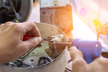 Technician man repairing the electronic laboratory equipment by soldering irons.