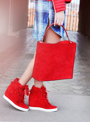 Slim tanned woman wearing red high heels with tassels and red bag with fringe.Street fashion....