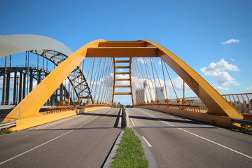 Fototapeta premium Jasnożółty most o nazwie Hogeweidebrug nad kanałem Amsterdam-Ren w Utrechcie dla ruchu i Vleutenspoorbrug, który jest mostem kolejowym.