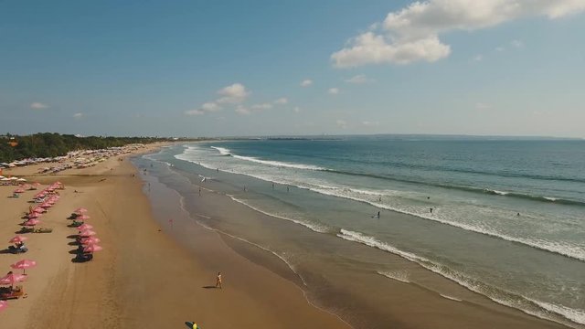 Aerial view of beautiful beach with surfers and tourists. Surfers enjoy the activity in Kuta beach in Bali, Indonesia. Beautiful view nice tropical beach from the air. 4K video, Travel concept, Aerial