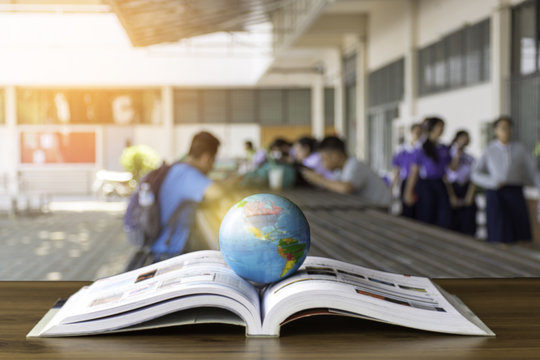 Global World Model Isolated On Opened Book With Students Using Technology Device Background. Technology Make People Get Knowledge As Travel Around The World. Education,knowledge And Reading Concept.