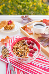 still life: granola with raspberries, waffles with raspberries and coffee surrounded by maple leaves