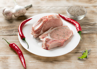 Raw pork ribs with red pepper, garlic and seasonings on a wooden background.