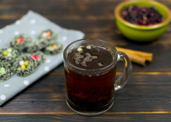 A cup with herbal tea and cookies on a dark background.