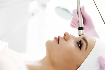 A woman came to laser hair removal facial. The woman lies and smiles, the doctor leads him in the face with a modern laser epilator. They are in the modern clinic.close up