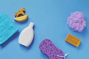 Flat lay bath products/ Terry towel, wooden horse, baby shampoo, purple sponges and natural soap. Top view photo bath products, cosmetics