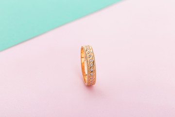 Pink gold wedding ring with diamonds and wave pattern on pink background