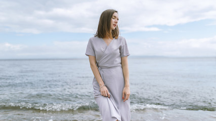 Woman in dress enjoys a walking near the sea shore.