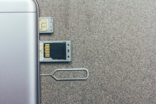 Mobile Phone And Open Slots For Nano SIM Cards, Micro SD Drive And Metal Key On Grey Background With Copy Space