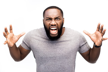 Portrait of dark-skinned African guy screaming with wide opened mouth in despair having unhappy, crazy, agressive, angry, dangerous expression. Frustrated male shouting loudly having aggression