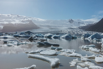 melting glacier ice floating in lake in Fjallsarlon, Iceland under blue sky