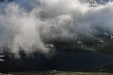 Mountain and clouds with a turquoise lake serene aerial view.