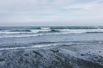ocean waves covering black sandy beach in Iceland