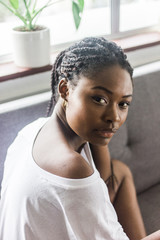 Fototapeta na wymiar Beautiful Black Woman With Braids Sitting On A Gray Couch At Home Portrait