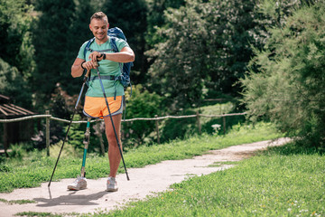 Optimistic motivated man with prosthesis trying up Nordic walking