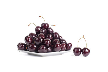 A lot of cherries in drops of water on a white plate isolated closeup macro