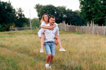 Young beautiful enamored couple walking outdoors in summer at sunset