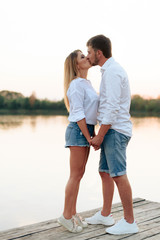 Young beautiful enamored couple walking outdoors in summer at sunset