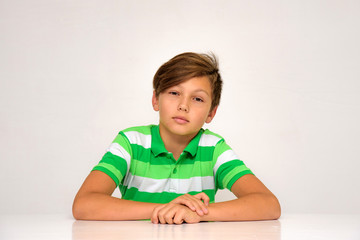 Naklejka premium Studio portrait of a teenage boy on a white background with different emotions sitting at a table.