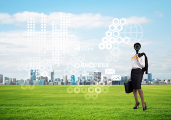 Camera headed woman standing on green grass against modern cityscape